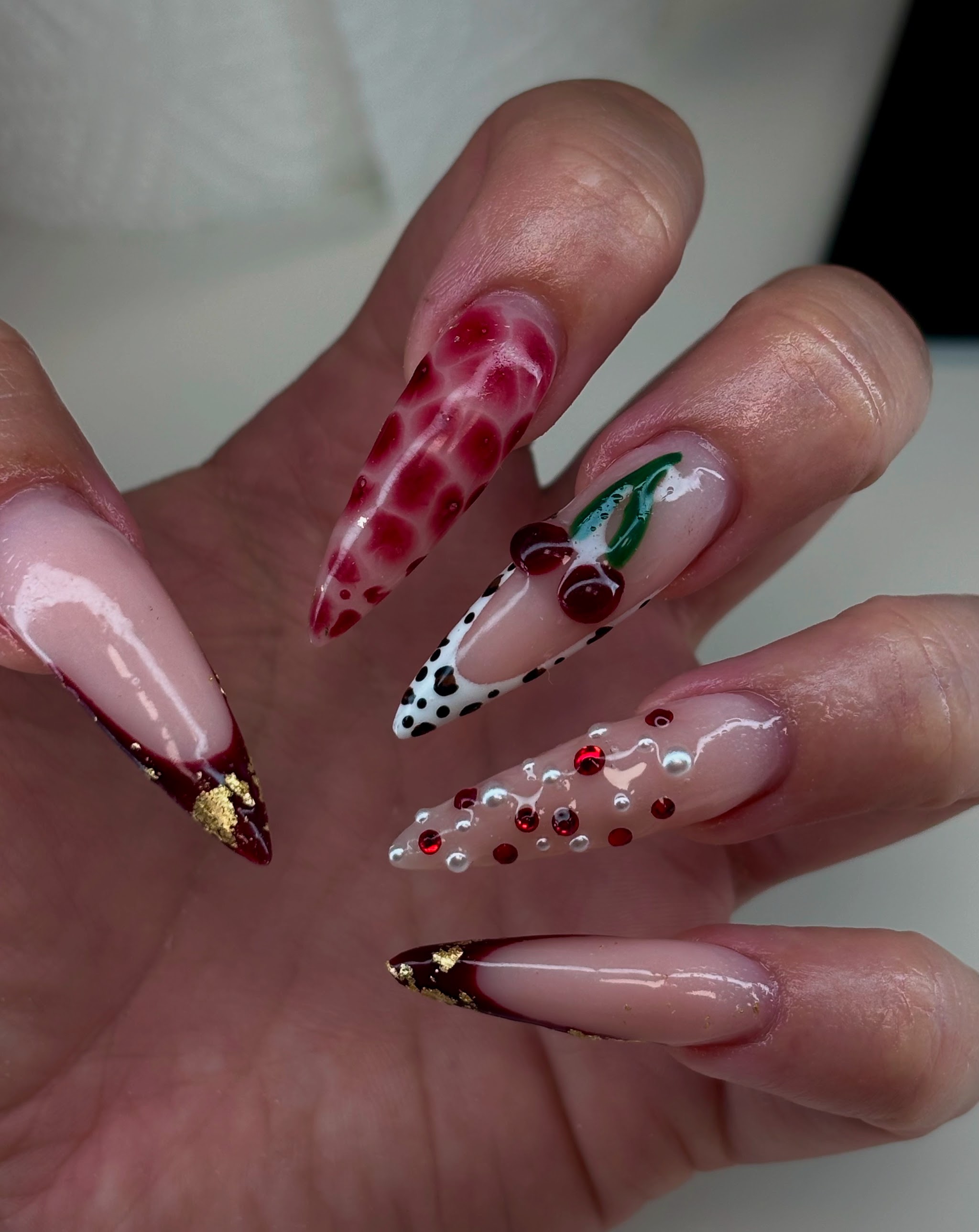 Lange amandelnagels met kersen, parels, rode print en gouden folie