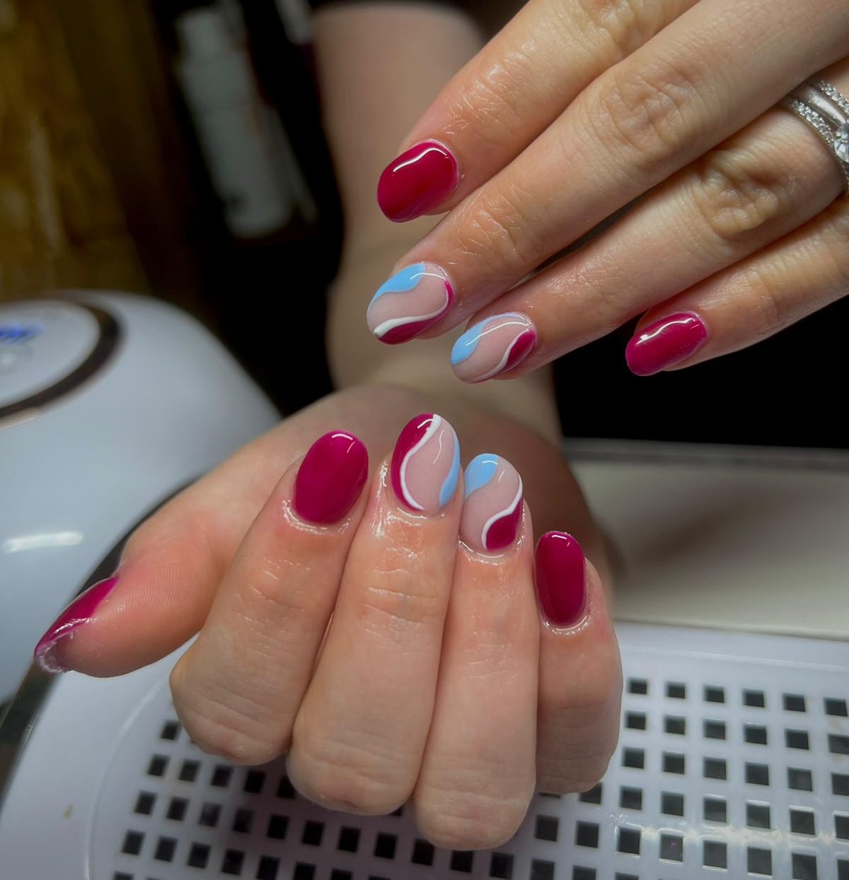 Frambozenrode nagels met blauw-witte swirls